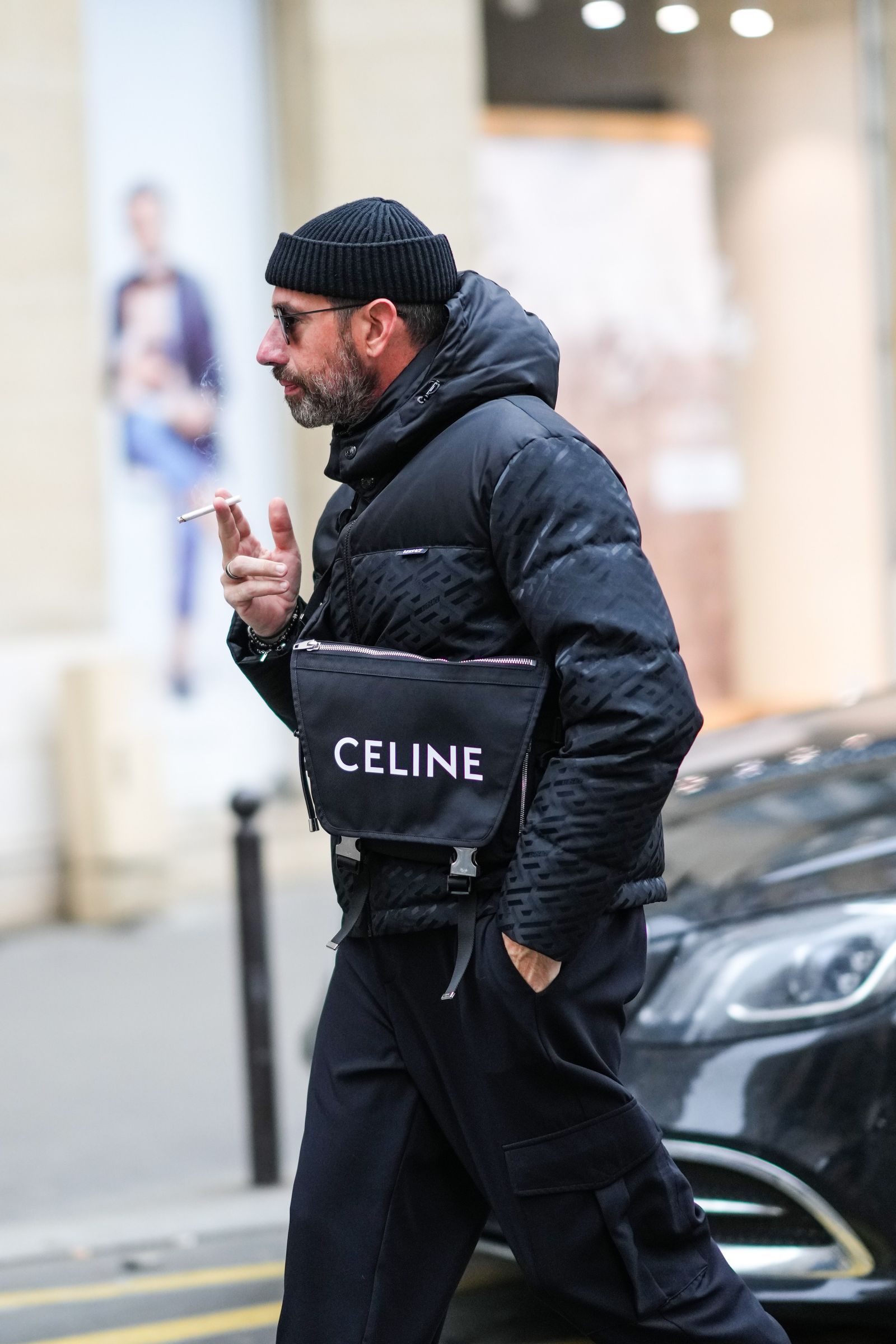 PARIS FRANCE  JANUARY 23 A guest wears black sunglasses a black ribbed wool beanie a black print pattern hoodie puffer...