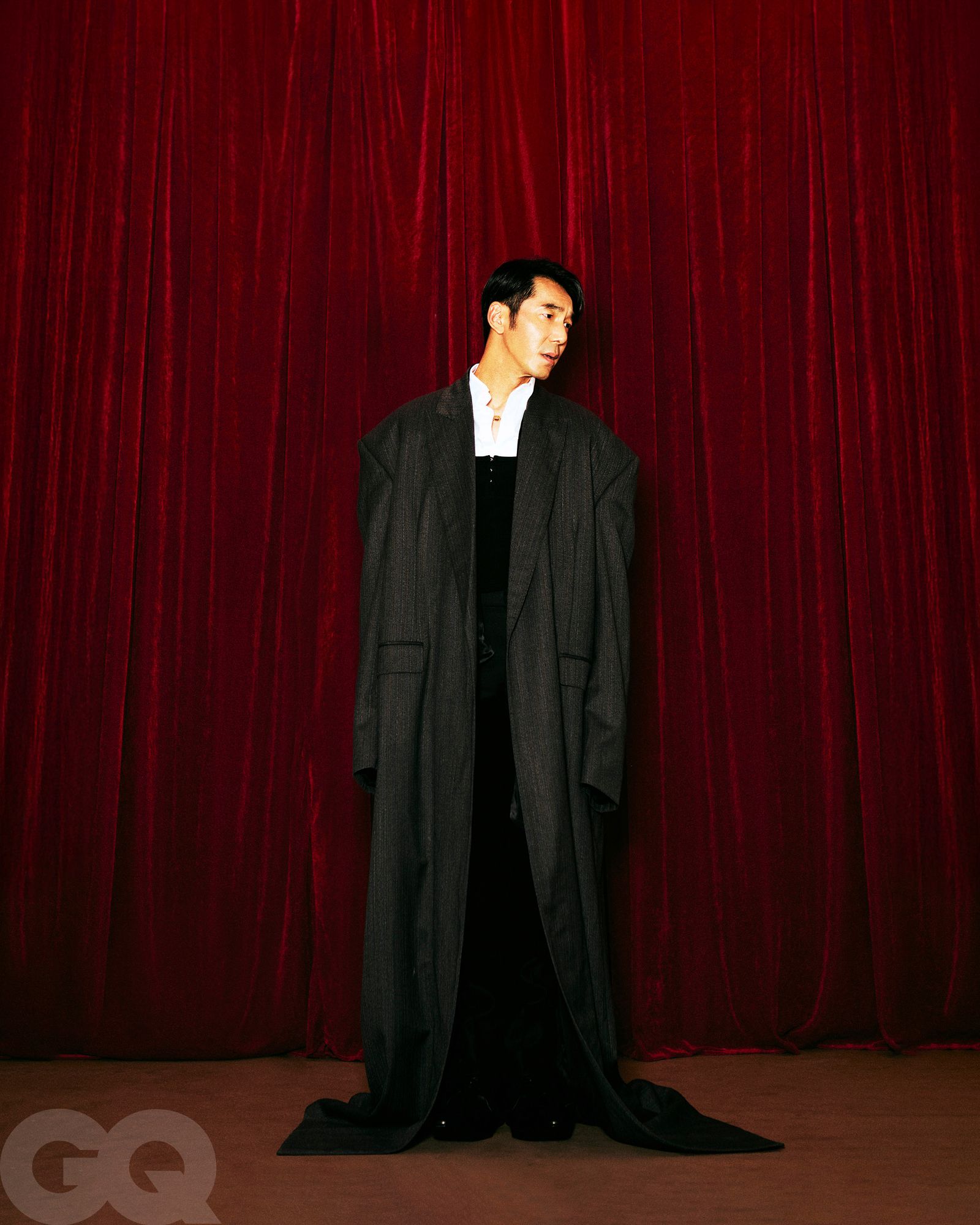 深灰色長大衣、尖頭皮鞋，都是Balenciaga。Loewe黑色西裝褲。Louis Vuitton紅寶石珍珠項鍊。白色襯衫、黑色背心、緞面綁帶，造型師私物。