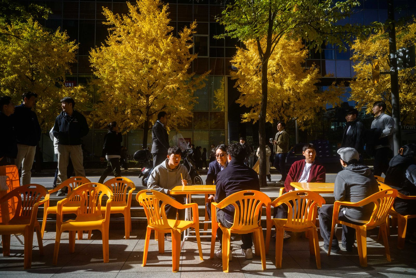 Customers sit at tables along a street as they wait for their coffee orders from nearby cafes in Seoul on November 14 2025.